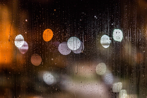 abstract background night street lights bokeh through wet glass with water smudges closeup with selective